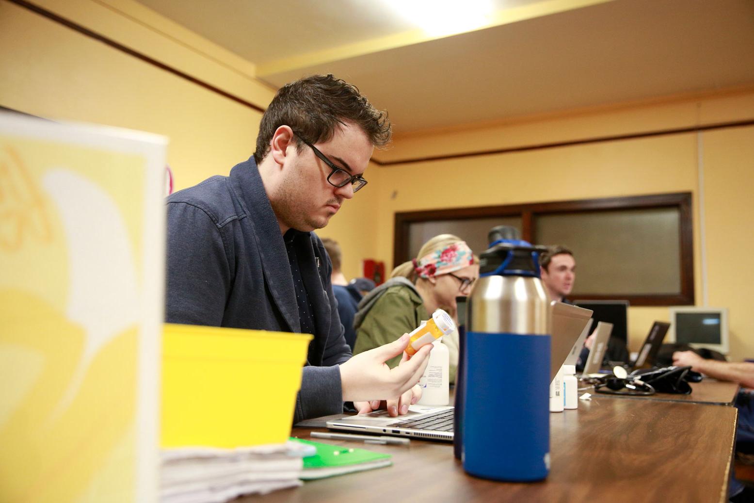 药店 student examines medication container in classroom